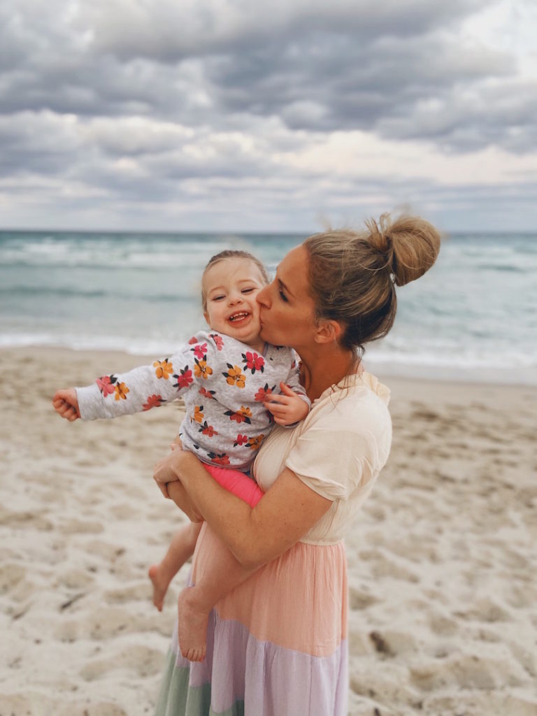 Brooke kissing her daughter on the cheek at the beach in Florida