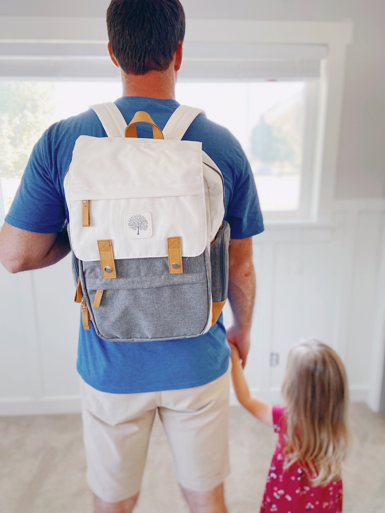 Dad wearing a gray and cream diaper bag backpack 