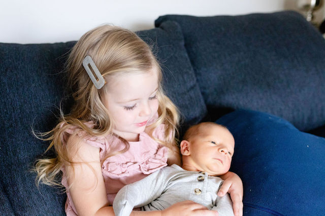 Big sister with new baby brother on the couch for newborn photo session